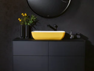 Modern bathroom design with a black Finion washbasin, a vibrant yellow Artis washbasin, a round mirror and a geometric light