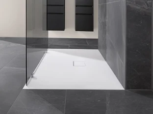 A minimalist shower area with a white Villeroy & Boch shower tray, a glass partition and dark grey tiles on the walls and floor, in the background there are two vertical black units on the wall.