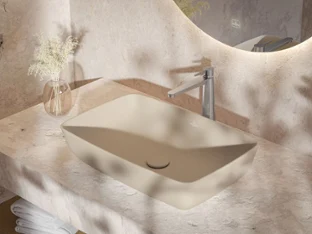 Beiges Artis Waschbecken auf Steinplatte mit Chromarmatur Ein modernes, rechteckiges Waschbecken in Beige mit einer verchromten Armatur auf einer Arbeitsplatte aus strukturiertem Stein, daneben eine kleine Vase mit Zweigen.