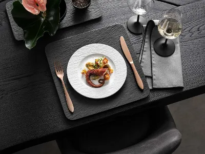 Une élégante salle à manger avec des plats gastronomiques, du vin et de la vaisselle moderne Manufacture Une élégante salle à manger avec des plats gourmands, du vin et de la vaisselle moderne Manufacture en noir et blanc sur une table en bois foncé.