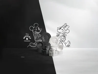 Una serie de platos y tazas blancos y negros de la colección Manufacture Mickey. Una serie de platos y tazas blancos y negros de la colección Manufacture Mickey, dispuestos sobre una superficie dividida en dos mitades, una blanca y otra negra.