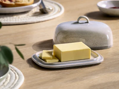 Perlemor Butterdose im Boho-Stil Ein rechteckiger Butterblock mit zwei Scheiben liegt auf einer Perlemor Butterdose aus Keramik mit passendem Deckel auf einem Holztisch.