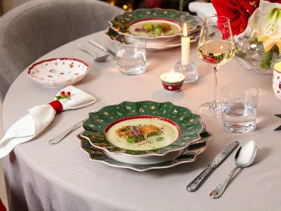 Toys Delight festively set for Christmas A festively set table with a bowl of soup, bread, cutlery, candles, a wine glass and Christmas decoration.