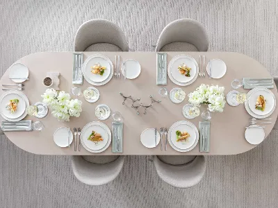 Afina Geschirr mit Piemont Besteck und leckerem Essen auf einem beigen Esstisch Eleganter Esstisch, gedeckt für sechs Personen, mit weißem Afina Geschirr, Piemont Besteck und leckerem Essen.