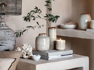 Perlemor Duftkerze neben Lave Vasen Ein Wohnzimmer mit Perlemor Duftkerzen, Lave Vasen und Büchern auf einem Regal.