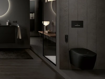 Modern bathroom with dark walls, floating vanity, round backlit mirror and black toilet; large window in the background.