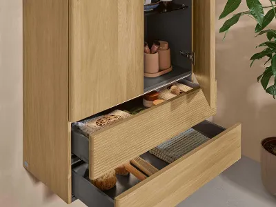 Highboard Antao in Holzstrukur im Badezimmer Ein Badschrank aus hellem Holz mit zwei Türen und zwei offenen Schubladen von Villeroy & Boch an einer naturbelassenen Wand.