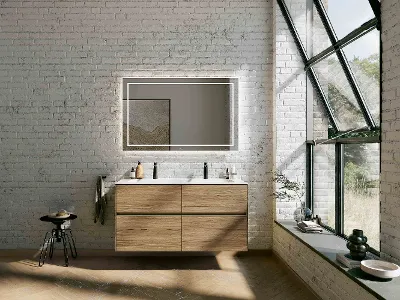 Braunes Finion-Doppelwaschbecken mit beleuchtetem Spiegel Modernes Bad mit schwebendem Finion-Holzwaschtisch, großem beleuchtetem Spiegel, Ziegelwänden und großen Fenstern. Es hat einen schwarzen Hocker und Dekoration auf der Ablage und entlang der Fensterbank.