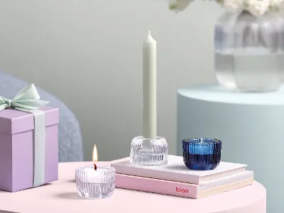 Three Villeroy & Boch Fleur glass candle holders Three Villeroy & Boch Fleur glass candle holders, a gift box and books arranged in a modern setting on a pink table.