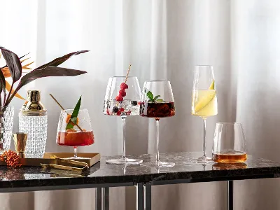 Elegante MetroChic Gläser mit verschiedenen Cocktails auf einem Marmortisch Verschiedene Cocktails in eleganten MetroChic Gläsern auf einem Marmortisch neben einer Pflanze.