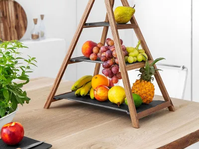 Un'alzata Artesano dal design triangolare in legno presenta diversi frutti. Un'alzata Artesano di Villeroy & Boch dal design triangolare in legno presenta vari frutti come banane, uva, pere e una mela su un tavolo da cucina.