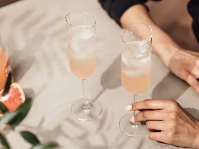 La personne tient une coupe de champagne NewMoon avec une boisson pétillante à l'intérieur