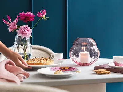 Rose Garden Geschirr und Vase auf einem Esstisch beim Servieren vom Dessert Eleganter Esstisch mit einer Person, die das Dessert serviert, frischen Blumen in Rose Garden Vasen und Tellern aus der Kollektion Rose Garden, die das Ambiente verstärken.