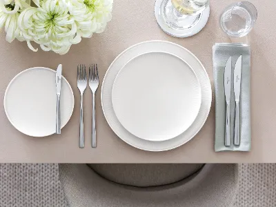 Table dressée avec de la vaisselle Afina qui donne l’impression de flotter dans l’air Une table dressée avec des assiettes Afina vues de côté pour voir l’effet aérien des assiettes qui semblent flotter dans l’air.