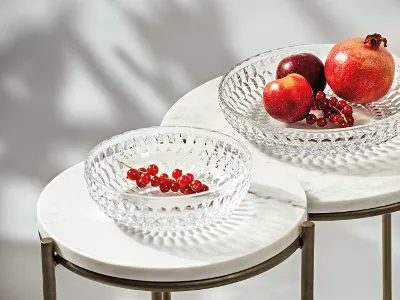 Des coupes en verre Boston sur des tables en marbre avec des fruits Deux coupes en verre transparent Boston sur des tables en marbre avec des fruits. L’une contient des grenades et une pomme, l’autre des groseilles rouges.