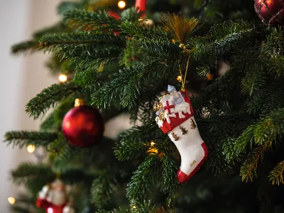 A Christmas tree decorated with lights, red light bulbs and a stocking decoration from Villeroy & Boch
