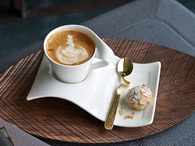 Une pause-café savoureuse avec une tasse NewWave et une cuillère raffinée Une tasse NewWave avec du latte art et des biscuits sur une table en bois, accompagnés d’une cuillère NewWave raffinée.