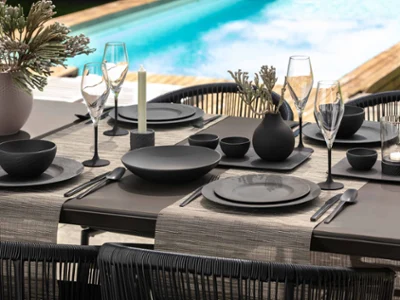 Black Manufacture crockery and glasses on a table by the pool Elegant outdoor dining area with black crockery and glasses from the Manufacture collection beside a pool.