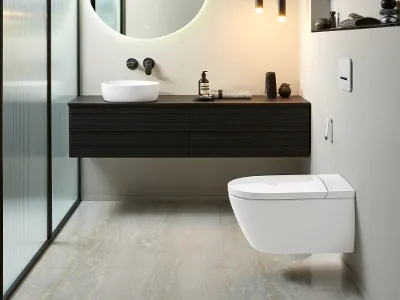 Antao Kollektionsbad mit ViClean Dusch-WC von Villeroy & Boch Modernes Badezimmer mit wandmontiertem WC, schwebendem schwarzen Waschtisch mit weißem Becken, beleuchtetem runden Spiegel, Hängelampen und Trennwand aus Milchglas.
