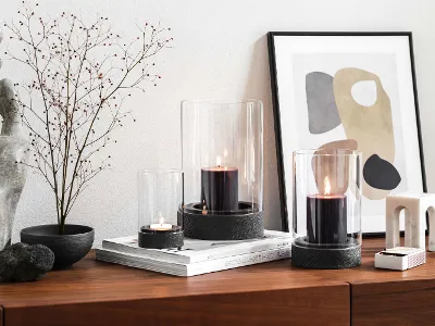 Eine moderne Wohneinrichtung mit einem hölzernen Sideboard und Trockenblume mit drei Manufacture Windlichtern. 
