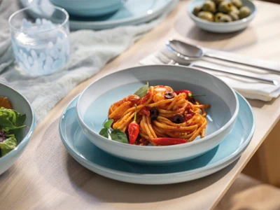 A pasta bowl stands on a blue Perlemor aqua plate. Adorn your table with pottery-style porcelain