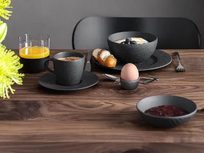 Manufacture di un set per la colazione su un tavolo di legno Un set per la colazione con caffè, succo, croissant, marmellata e un uovo sodo su un tavolo di legno, si vedono fiori verdi