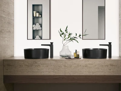 Modern bathroom with two black vessel sinks, black faucets, and a stone countertop. Two mirrors are mounted on the wall.