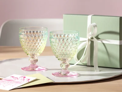 Dos vasos Boston Pearl con caja de regalo Dos vasos Boston Pearl de Villeroy & Boch están sobre una bandeja en una mesa junto a una caja de regalo verde claro atada con un lazo.