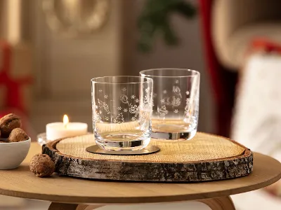 Two Toy's Delight glasses on a wooden disc Two Toy's Delight glasses on a wooden disc with a candle and a bowl of walnuts on a table.