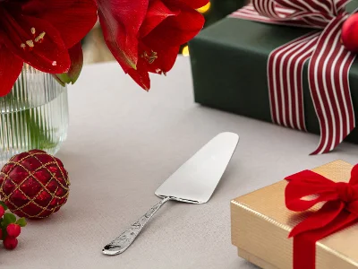 Une pelle à tarte sur une table avec des fleurs rouges, des cadeaux emballés et des décorations de Noël.