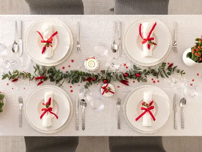 Festive dining table setting for Christmas with Manufacture plates Festive dining table setting for Christmas with Manufacture plates, red ribbons, and Christmas decorations.