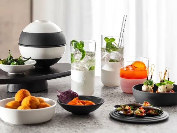 La petite Boule black and white on a marble countertop Black and white La petite Boule presenting various starters on a marble countertop, including deep-fried canapés, purple crisps, skewers and drinks with garnishes.