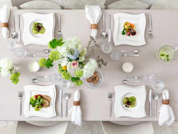 Refined Table Setting with NewWave, Boston & Freshly Plated Dishes Draufsicht auf eine moderne, minimalistische Tischszene mit NewWave Suppen-, Speise- und Frühstückstellern, angerichtet mit Speisen. Ergänzt durch Boston- und Boston-Green-Gläser sowie eine Mischung aus Blacksmith- und NewWave-Besteck. Eine klare, elegante Atmosphäre mit Liebe zum Detail und zur Präsentation.