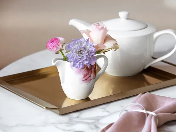 Rose Garden creamer pitcher with flowers on a golden tray Elegant tea serving set with a white For Me teapot and a Rose Garden creamer pitcher decorated with fresh flowers on a golden tray.