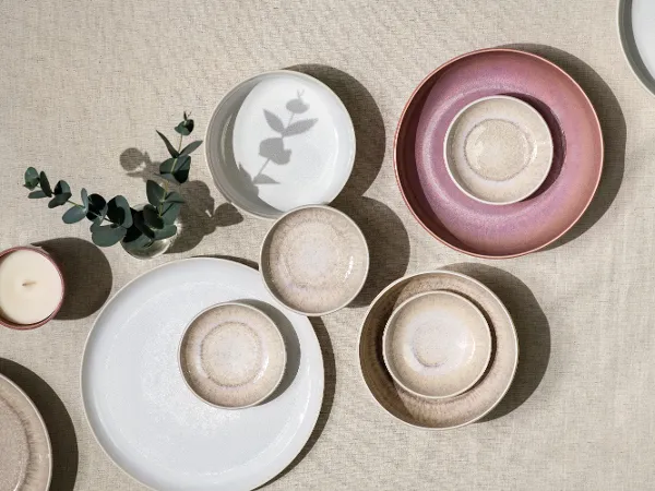 Verschiedene Crafted und Perlemor Teller auf einer strukturierten Oberfläche Crafted und Perlemor Teller in Pastelltönen, arrangiert auf einer neutral strukturierten Oberfläche.