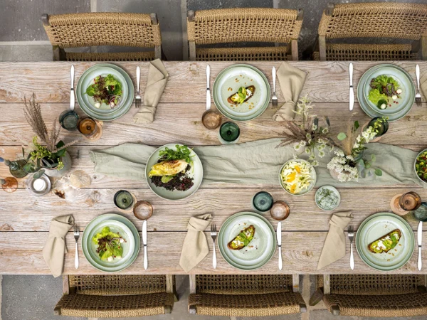 Vista superior de una mesa de comedor para seis personas con platos Perlemor Vista superior de una mesa de comedor rústica para seis personas con platos Perlemor, bebidas y flores decorativas.