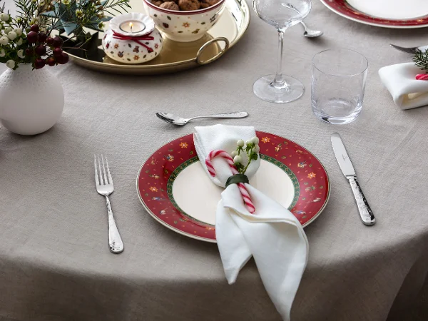 Une assiette rouge festive Toys Delight associée à un photophore, parfaite pour une table de Noël chaleureuse.