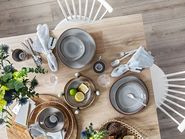 Modernen Esstisch gedeckt mit Lave Tellern, silbernem Besteck, Gläsern mit Limette und weißen Stühlen auf einem Holzboden.