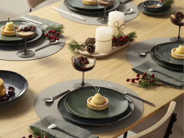 Elegant holiday Lave table set with desserts, candles, greenery, and berries on a wooden table.