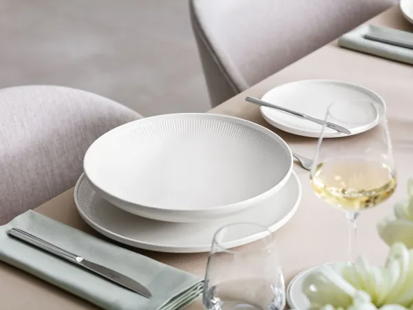 Piatto fondo Afina su una tavola apparecchiata Un tavolo con un bicchiere di vino e una tavola apparecchiata con piatti Afina di Villeroy & Boch.