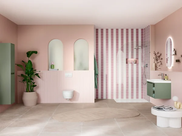 Cuarto de baño moderno con paredes rosas, zona de ducha a rayas, detalles en verde, grandes espejos y una planta en maceta.