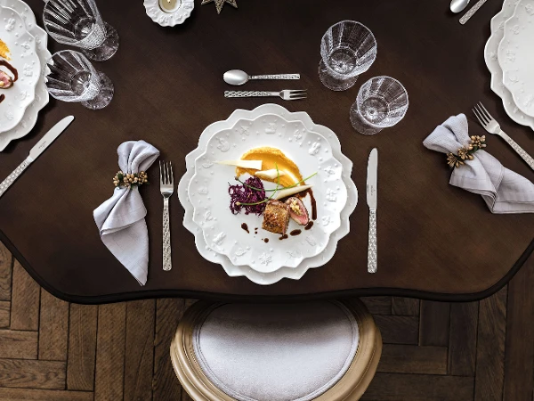 A festive table setting with Toy's Delight Royal Classic plates A festive table setting with Toy's Delight Royal Classic plates with gourmet food and cutlery on a round table.