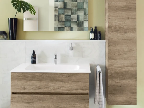 Arto washbasin with wood-look furniture A modern bathroom with a wooden washstand and cabinets, a washbasin, a towel, houseplants and a mirror on a yellow-green wall.