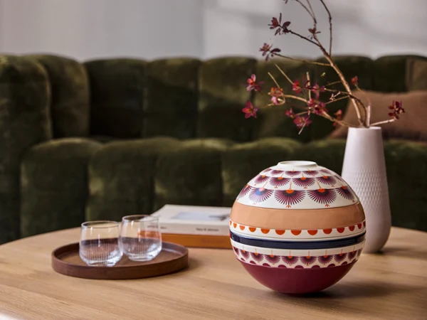 A La Boule Kyoto and a tray of glasses on a wooden coffee table in front of a green sofa.