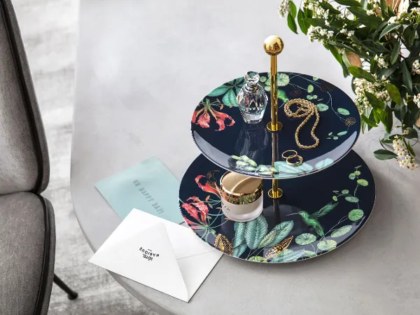 Avarua Etagere mit Schmuck auf grauem Tisch Eine Avarua Etagere auf einem Tisch oben drauf ein kleines Parfümfläschchen, Schmuck und ein Cremetiegel.