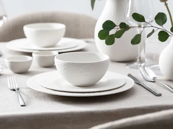 Manufacture dinnerware with simple decoration Elegant, white dinnerware set from the Manufacture collection on a table with simple decoration.