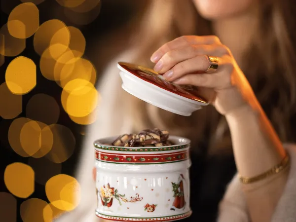 Una persona apre una scatola di biscotti Winter Bakery Delight. Una persona apre una scatola di biscotti Winter Bakery Delight su uno sfondo di luci calde e festose.