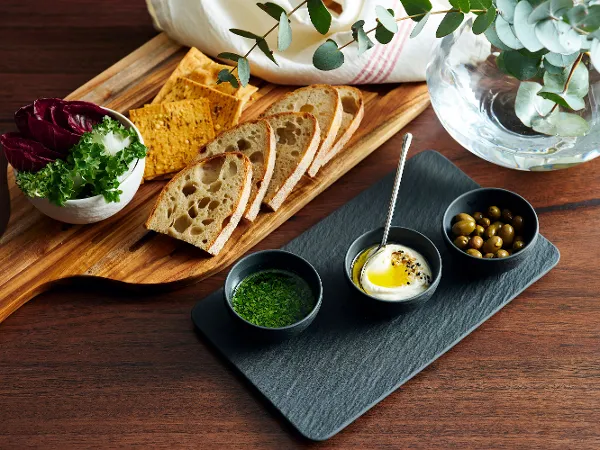 aus-manufacturerockblack-indoor-food-nopeople-dipset9023 The Manufactured Rock black 4pcs dip set, filled with fresh ingredients, is paired alongside a wooden board with fresh bread and a side salad on a rustic wooden table. Complemented by a white linen napkin.