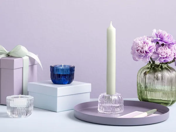 Three Villeroy & Boch Fleur glass candle holders and a Fleur Vert vase The Villeroy & Boch Fleur Vert vase with purple flowers is displayed on a surface next to gift boxes and Fleur candle holders.
