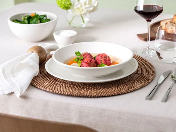 Close-up view of a table setting featuring Villeroy & Boch Artesano Original dinner plate and pasta bowl. The image captures the fine craftsmanship and natural design of the porcelain, styled in a warm, authentic table scene.